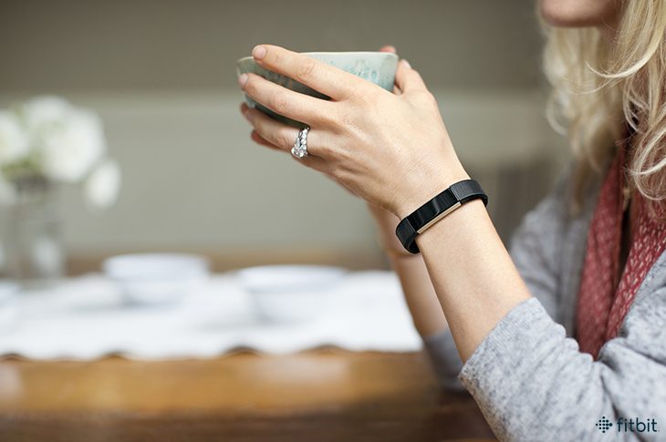 Woman holding a mug wearing a Fitbit