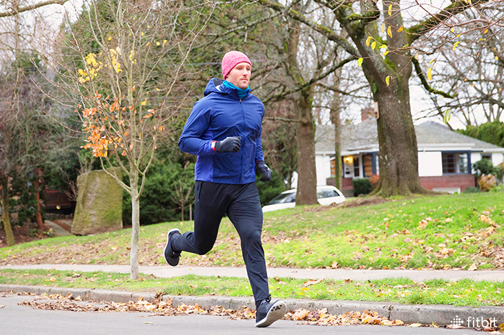 Man running in cold weather wearing a Fitbit tracker.