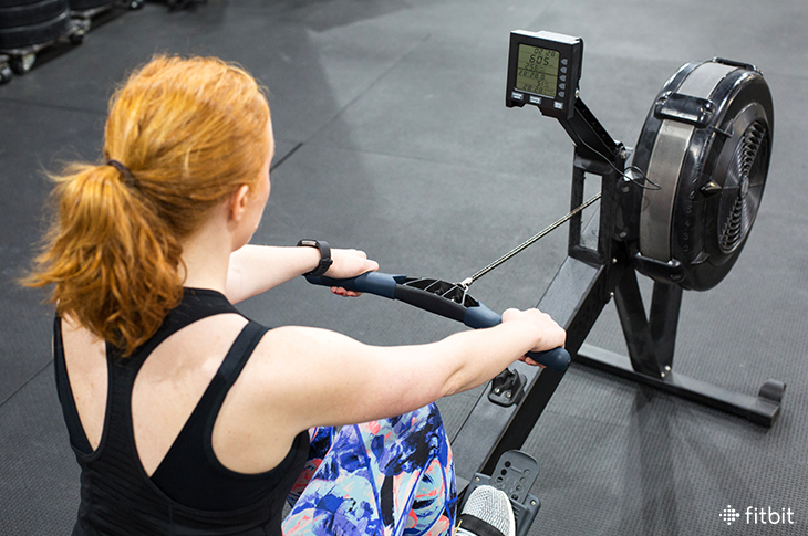 Woman doing a rowing workout indoors on an erg