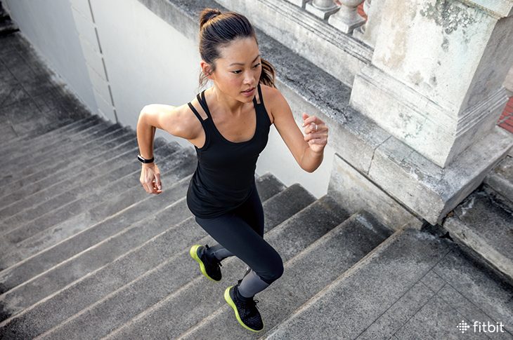 Woman running stairs while wearing a Fitbit tracker