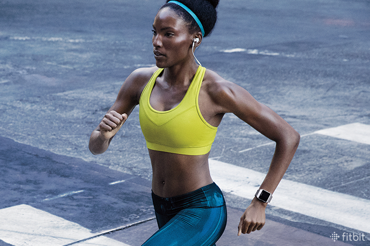 Woman running with Fitbit Ionic and Fitbit Flyer